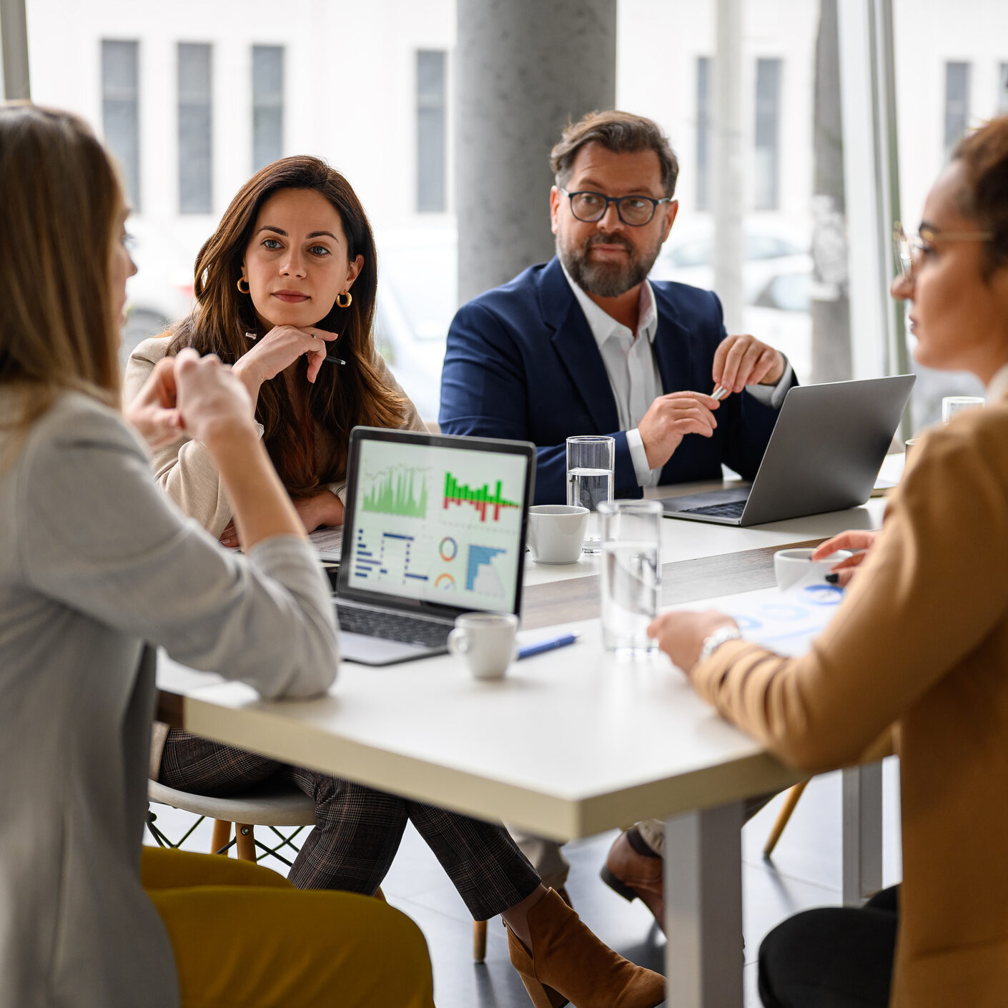 Businesswoman Reviewing Report On Her Laptop While Discussing Business Growth With Coworkers In Meeting